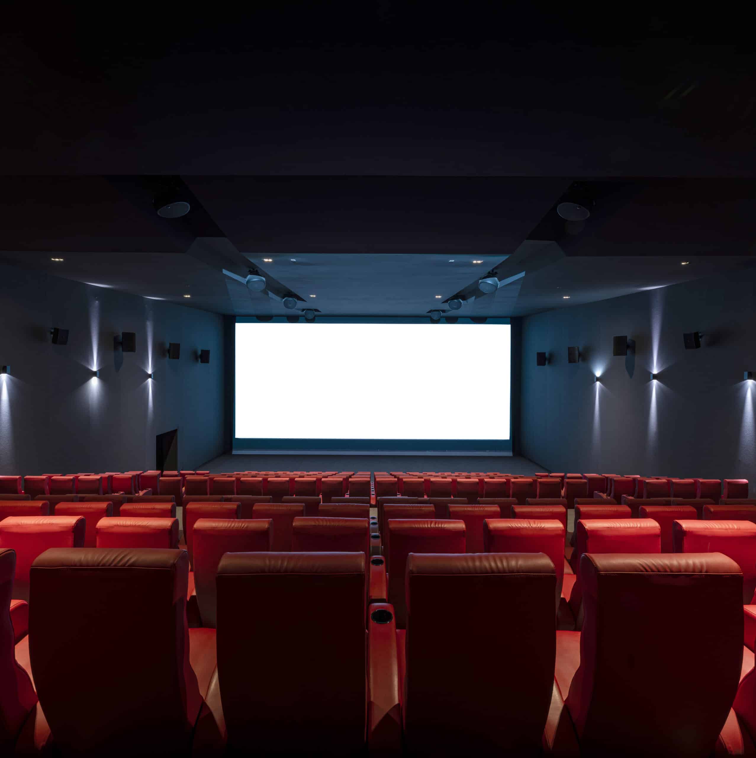 Vue depuis l’arrière d'une salle du cinéma Pathé avec ses rangées de fauteuils en velours rouges orientés vers l’écran.